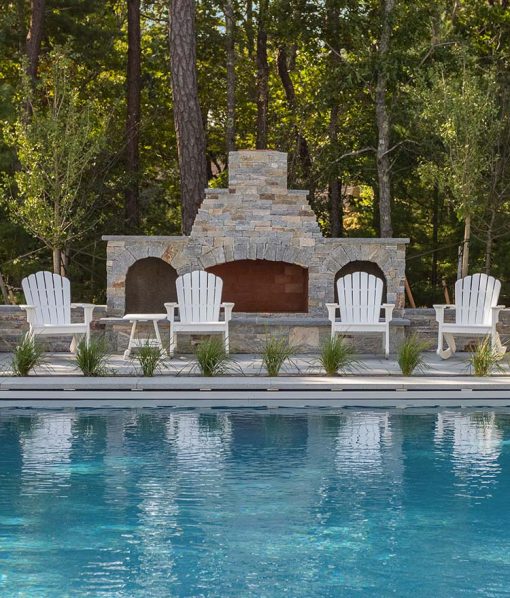 Fireplace by pool with chairs and stone veneer