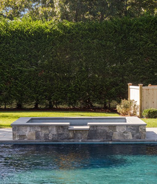 natural stone jacuzzi by backyard pool