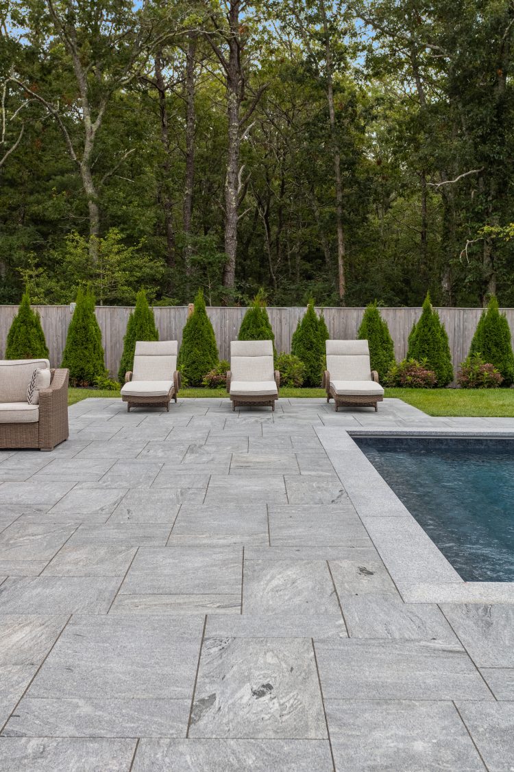 Unique silver granite pavers with intense movement surrounding beautiful backyard pool