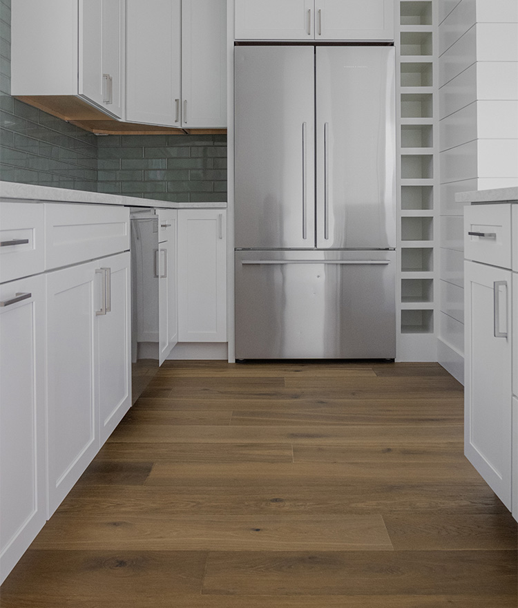 White kitchen with brown natural french oak flooring and stainless steel appliances.