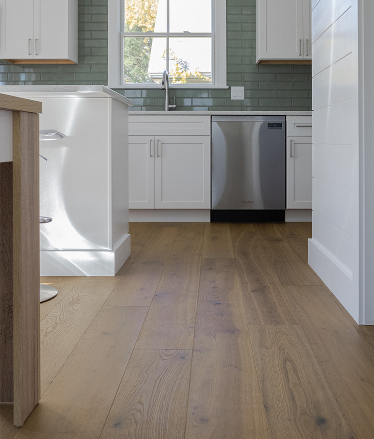 Wide plank brown natural flooring in white kitchen setting