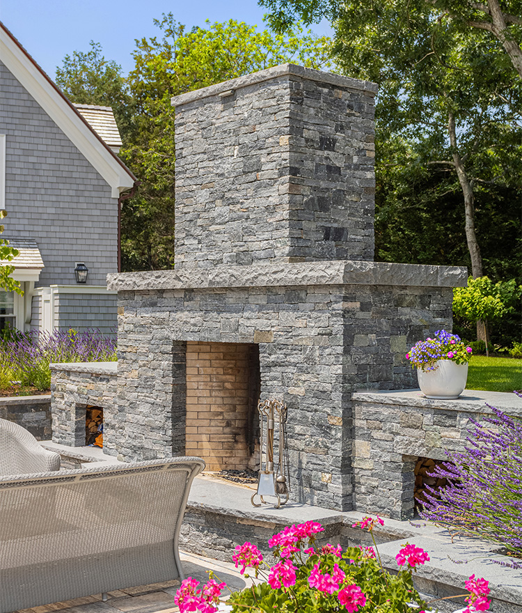Backyard fireplace with gray ledgestone veneer and corner pieces